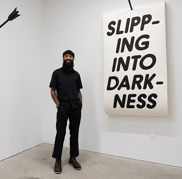 Chris Martin posing with one of his art pieces 