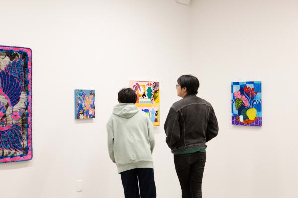 Two people look at Mary Finlayson's painting at the opening reception of Oddkin, a group exhibition in a contemporary art gallery.