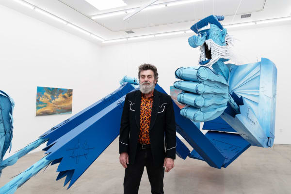 Artist Wayne White at Hashimoto Contemporary Los Angeles in front of his puppet for his solo exhibition Jumping From Ice Floe to Ice Floe
