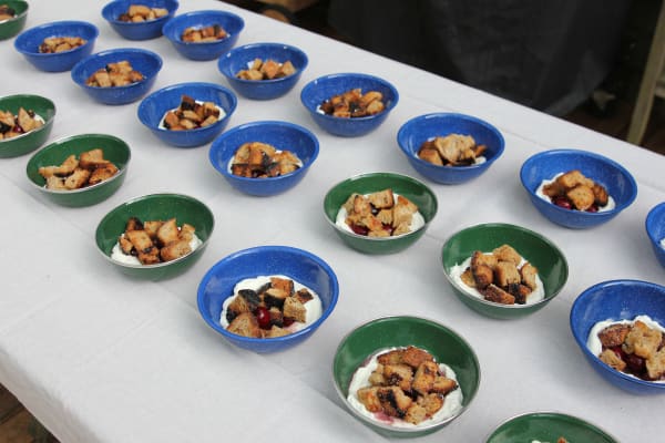 A dessert of caramelized bread soaked in wine and stewed cherries on a bed of freshly whipped cream