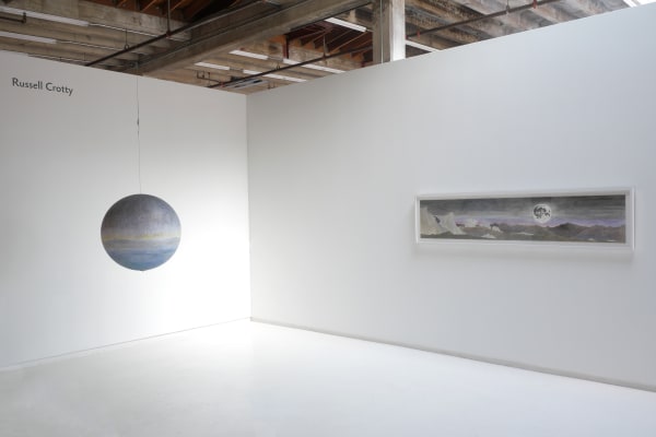 Installation shot of artist name ("Russell Crotty," left, top), hanging globe (left) and panorama drawing (right)