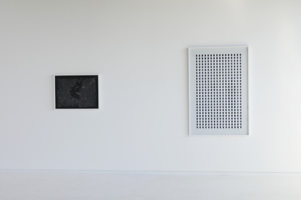 The image shows two framed artworks displayed on a white wall. The artwork on the left is a smaller square piece featuring a black background with a scattered pattern of small white and red dots, creating a textured effect. The artwork on the right is a l