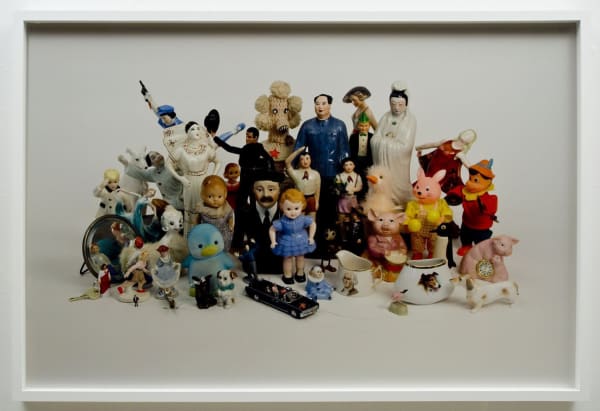 Duraflex print of a digital photograph which depicts a clustered group of variously sized figurines and found objects in front of a white background. The figurines are arranged so that the tallest ones are in the middle and the shorter ones are along the