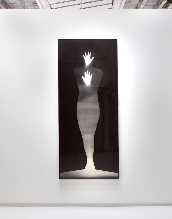 Large work by Bruce Conner depicting the silhouette of person colored in by the sky amongst black background with white hands touching surface towards viewer.