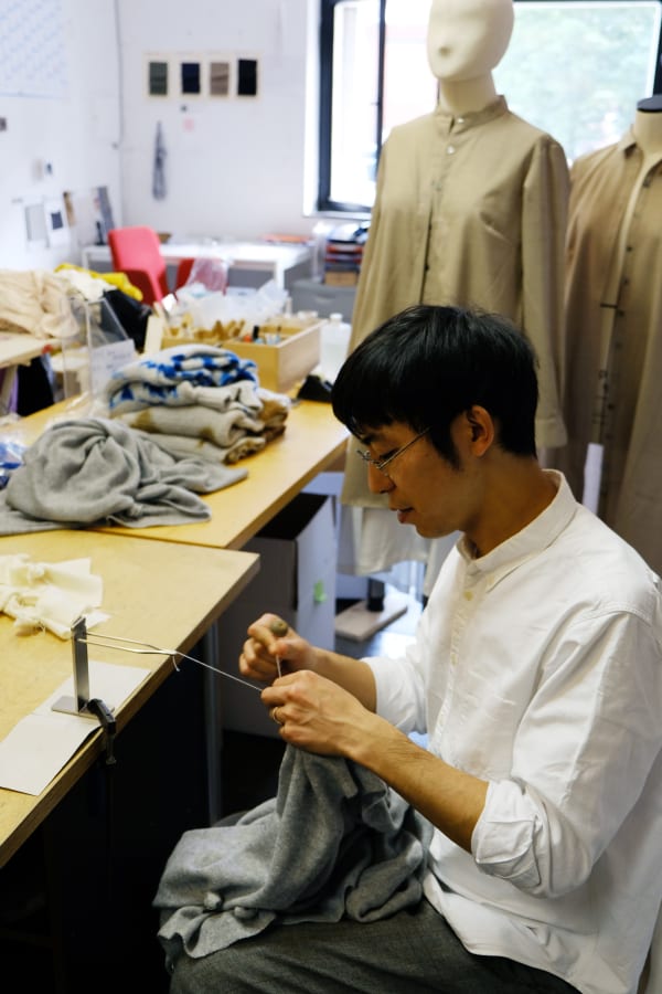 Hiroyuki Murase sits in his work shop, sewing.
