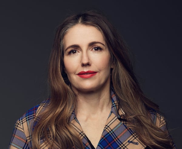 Headshot of a brunette woman in a plaid jacket.