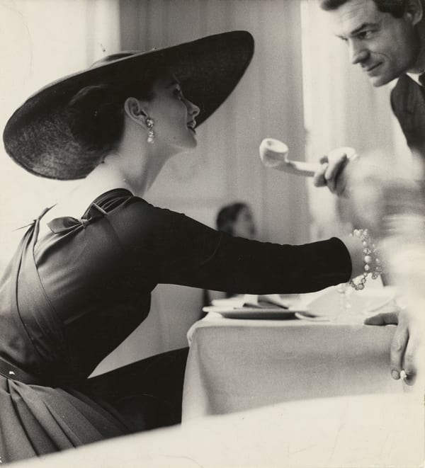 fashionable woman in hat at restaurant receiving telephone from waiter