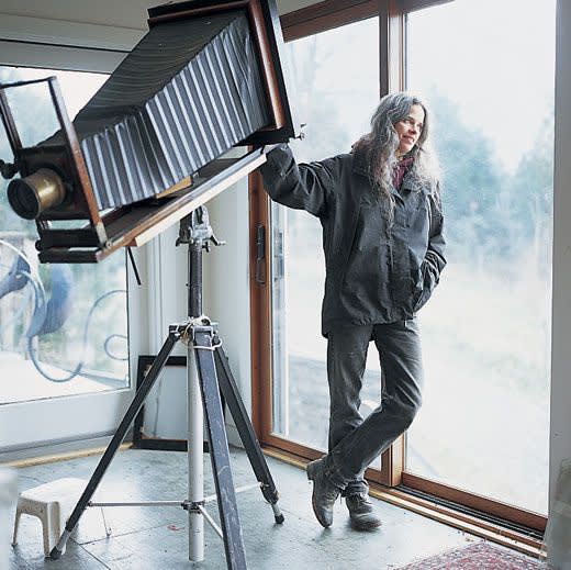 Sally Mann with an old view camera leaning against window