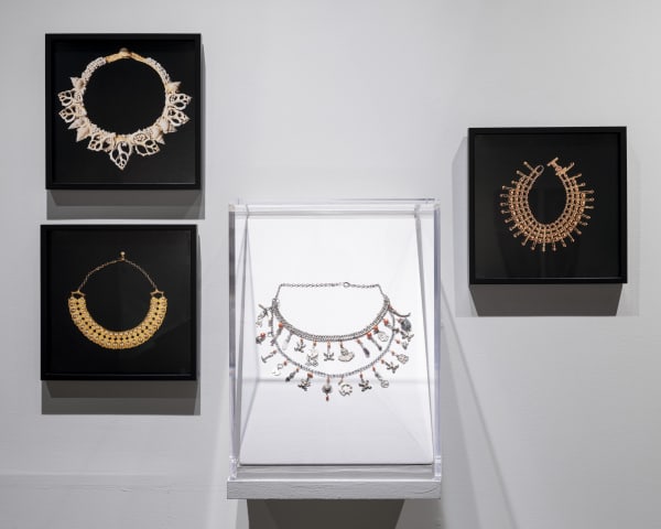 Installation photograph of three photographs of Ruth Bader Ginsburg's collars by Elinor Carucci with amulet necklace from the collection of the Jewish Museum by Kris Graves