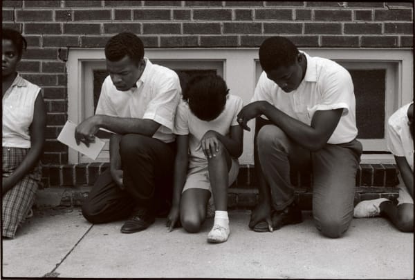five Black young protestors including John Lewis kneel to pray on the street by Danny Lyon