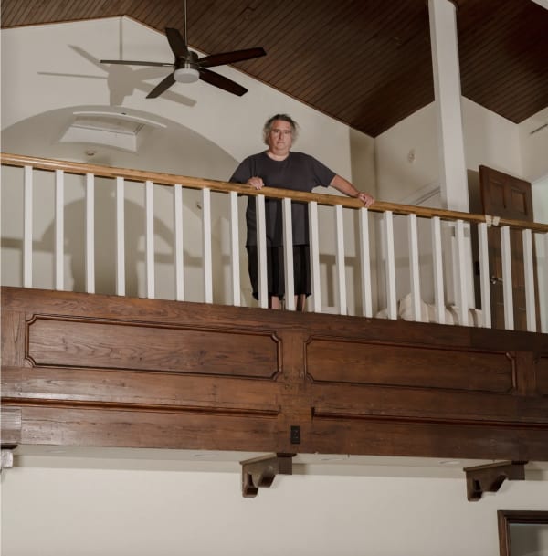 Gregory Crewdson standing on a balcony with his hands on the banister in a former Methodist church, built in 1890, on the outskirts of Great Barrington, Mass.