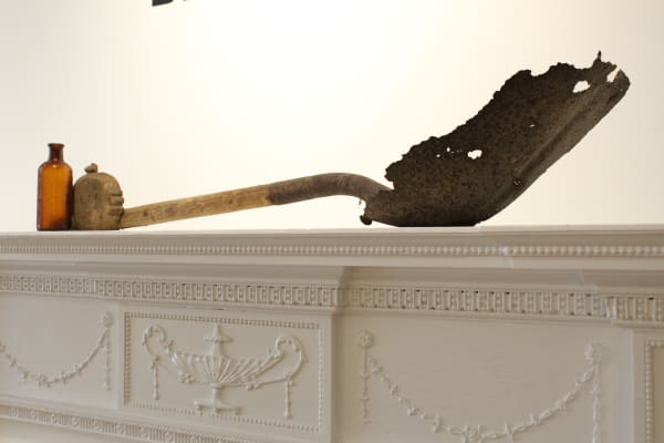 Omar Tate Reclamation Project Reclaimed artifacts taken from the land that used to be the White Hill Plantation in Orangeburgh, SC where his ancestors were enslaved. A shovel, a medicine bottle and a wood carving al representing different aspects of the existence in that space. The enslaver, Dr. Van de Vestine Jamison is represented in the bottle as he was a physician, the shovel represents the forced labor and work of the life as an enslaved human, and the carving represents their humanity, brain, desires and intellect.
