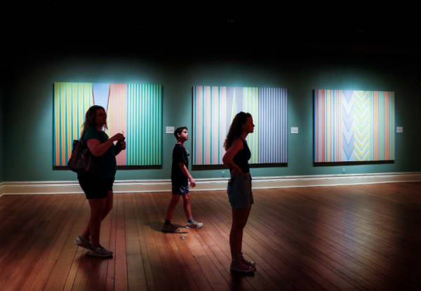 Visitors look over the artwork of painter James Little at The Dixon Gallery and Gardens’ “Sweet 16” exhibit on Tuesday, May 23, 2022. (Mark Weber/The Daily Memphian)
