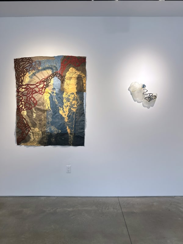 photo of an installation with one large work on paper hanging next to a small sculpture. Both are on the wall.