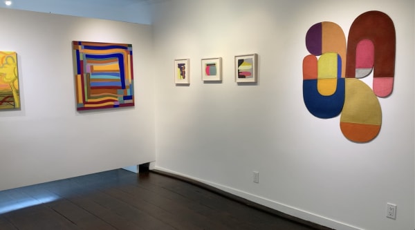 Six abstract colorful paintings of various sizes on two gallery walls