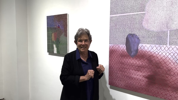 Woman standing in front of two abstract art paintings on a gallery wall