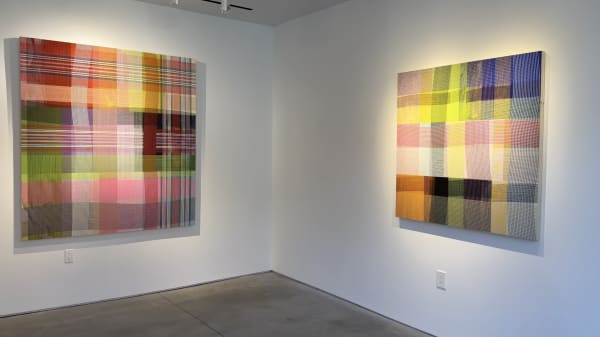 Two colorful geometric abstract paintings hanging on art gallery walls.