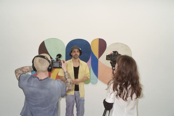 Man being interviewed by two people holding cameras.