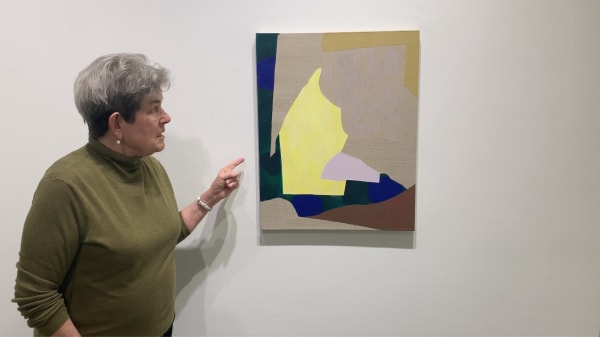 Kathryn Markel pointing at an abstract painting on the wall.