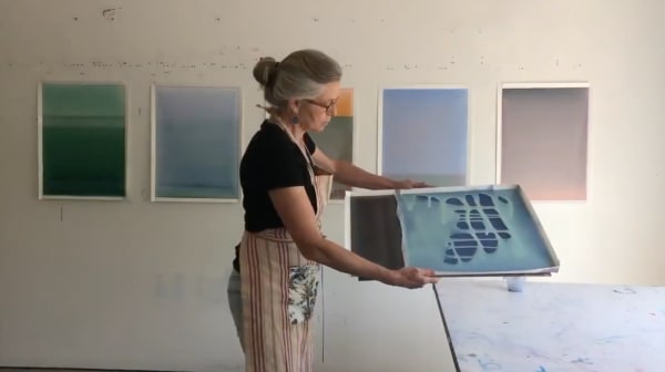 Artist Susan English in her studio pouring polymer on paper