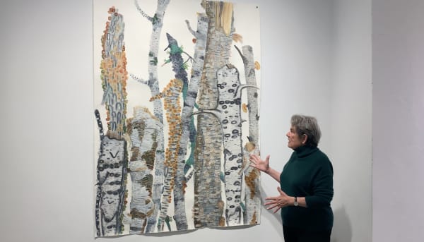 Woman looking at large watercolor painting of tree branches