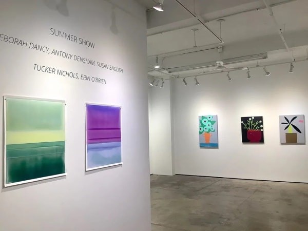 View of gallery exhibition featuring abstract and floral art paintings.