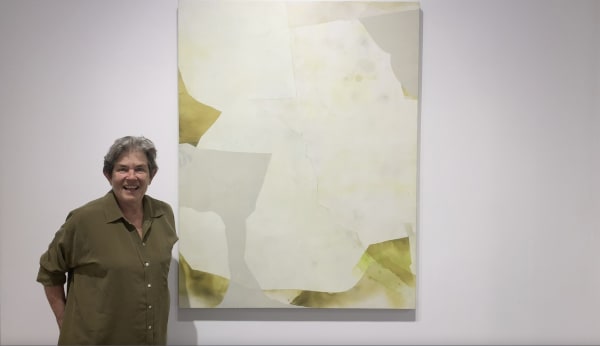 Woman standing in front of large yellow and white abstract painting.