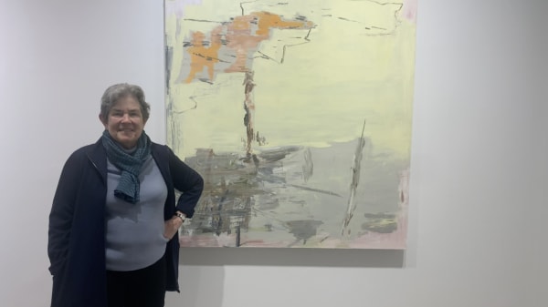 Woman standing in front of large abstract painting on a gallery wall.