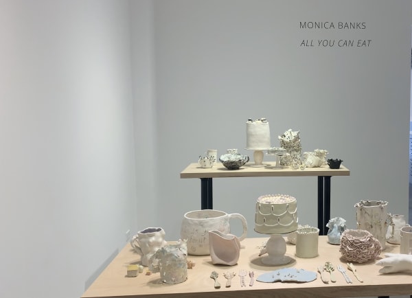 Numerous ceramic sculptures on tables in gallery