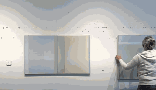 photo of back of artist hanging the painting on a studio wall