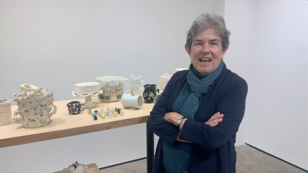 Woman standing in front of a table with ceramic sculptures.