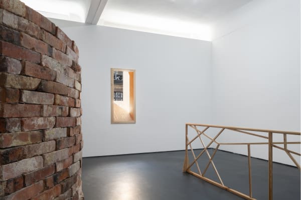 Installation view five | rindon johnson | Photo: Marjorie Brunet Plaza. White room with a window in a wooden frame, a curved red-brown brick wall and a wooden railing structure.