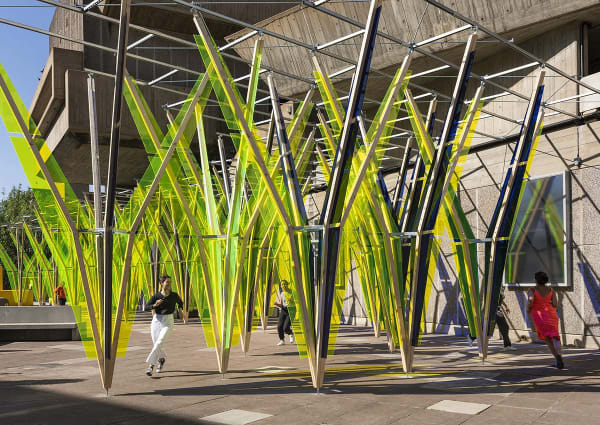 The Hop, (2022) Commissioned by the Hayward Gallery, London, UK Sculptural installation/pavilion Fluorescent live-edge Plexiglas, aluminium Unistrut, pine wood. 4m(h) x 5m(d) x 22m(l) Depth dimensions vary across the work.