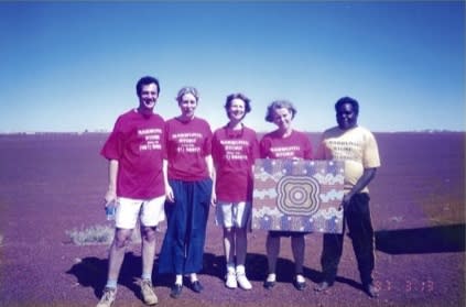 Rebecca Hossack In Balgo Hills with three colleagues and an artist, presenting a piece of Aboriginal artwork.