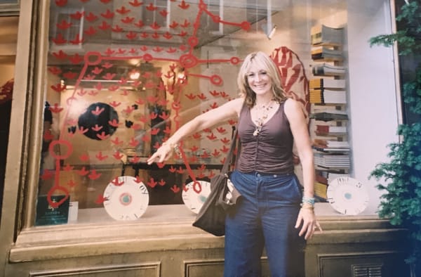 Rebecca Hossack in front of the Rebecca Hossack Art Gallery window, painted by Spinifex artist Roy Underwood