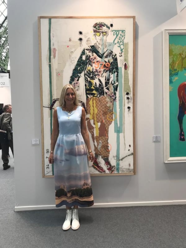 Rebecca Hossack at Art Paris in front of a Mersuka Dopazo painting