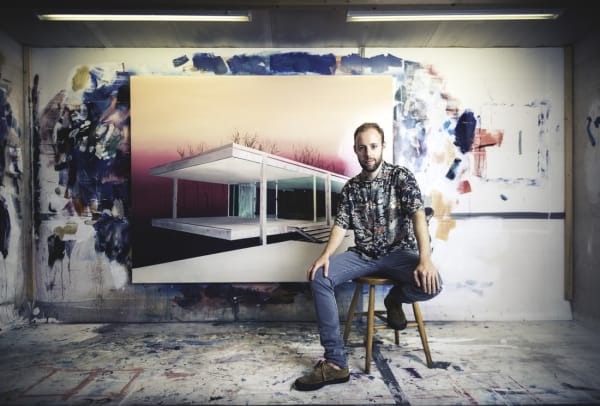 Laurence Jones sitting in front of one of his painting of LA house