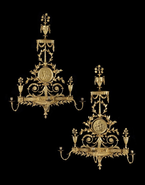 A PAIR OF GEORGE III GILTWOOD AND COMPOSITION WALL LIGHTS IN THE MANNER OF ROBERT ADAM