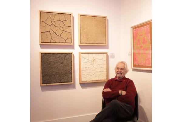 Frank Romero next to his work, The Adobe Series, 1995/2024 and Chicano Iconography, 1992 at De aquí y de allá: Frank Romero, A Survey, Ruiz-Healy Art, San Antonio. Image by Lauren Perales.