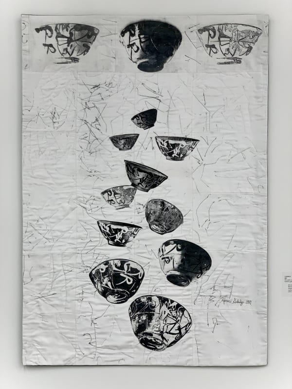 This quilt is hung vertically and features black-and-white transferred photographic images of the gifted ceramic Chinese bowl at the heart of the show, in different sizes. Three are positioned along the top band of the quilt, the others seem almost to “tu