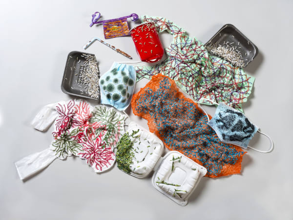This work consists of 10 separate pieces of various single use plastics pinned to the wall in a rectangular arrangement. Plastics such as a black styrofoam tray (cut into two pieces), a red plastic cup, a white and a green plastic bag, blue face masks, or
