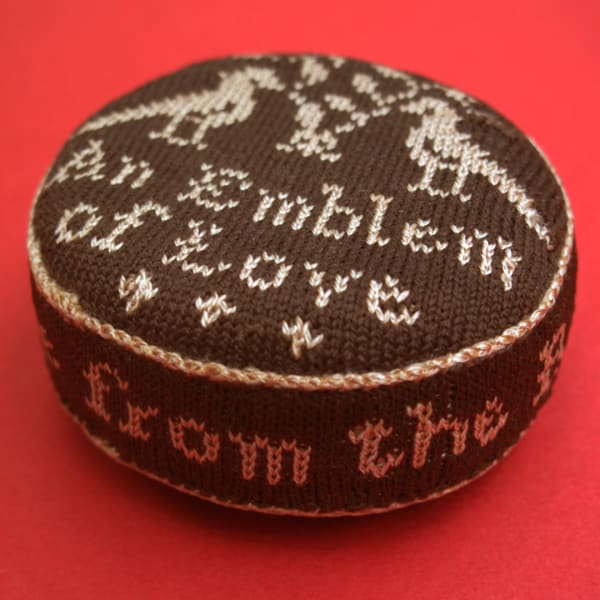 Early stitched emblem of love pin cushion.