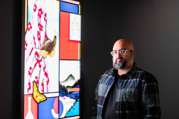 Amir H. Fallah stands beside his work Silent Traveler. The stained-glass piece is part of the Fowler Museum’s The Fallacy of Borders, a collection of more than 25 pieces by Fallah. (Ethan Manafi/Daily Bruin staff)