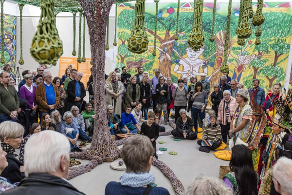 People gathered around crochet tree installation