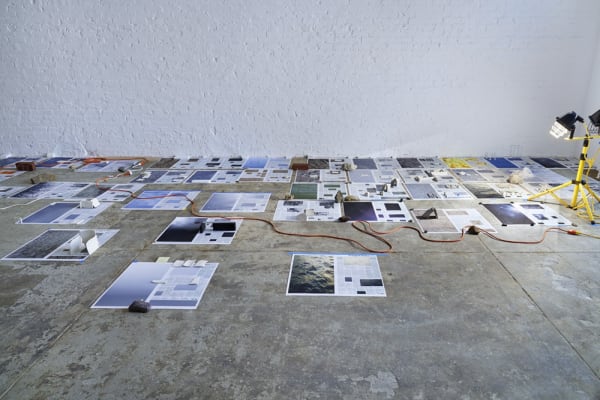 Installation view with newspapers on floor and rocks