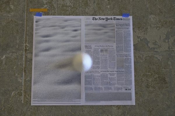 Installation view with newspapers on floor and rocks