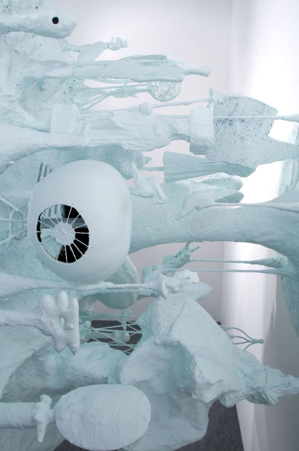 image of table-like sculpture mounted on wall with abstracted forms coming out from underneath the table