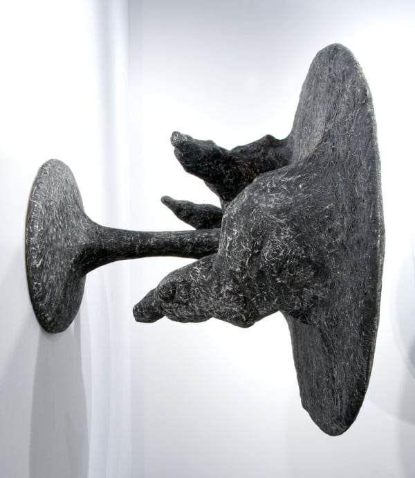 image of table-like sculpture mounted on wall with abstracted forms coming out from underneath the table