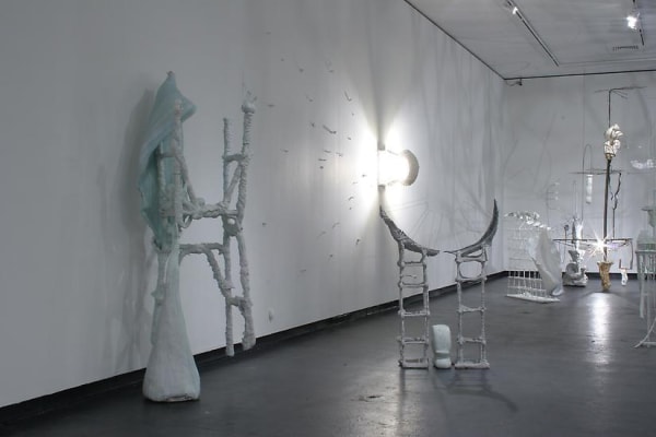 image of installation image of multiple Charles Long white sculptures, dim lighting and shadows
