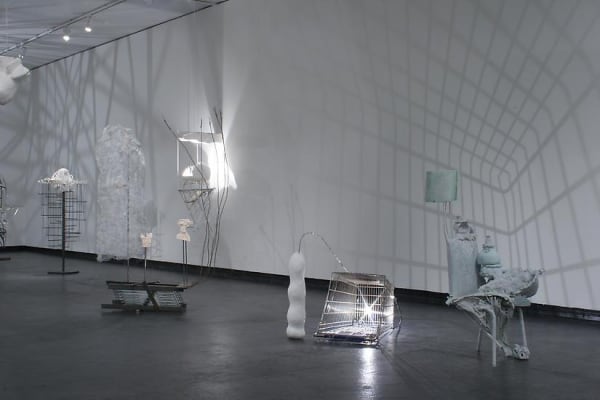 image of installation image of multiple Charles Long white sculptures, dim lighting and shadows